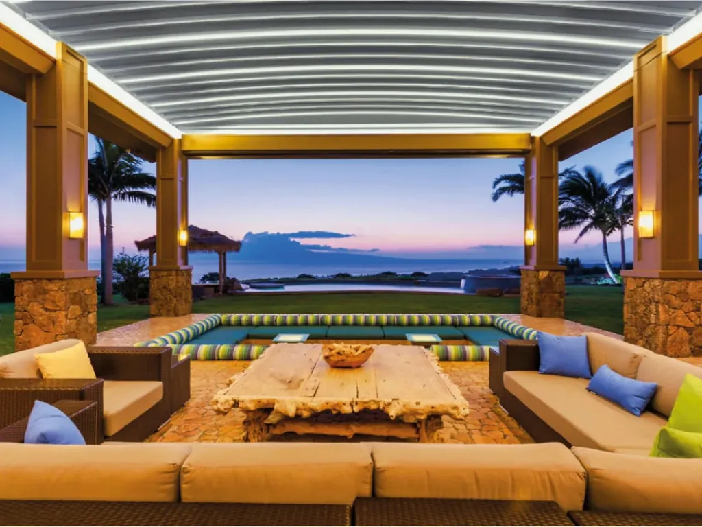 Pérgola PergoTek Design sobre un lounge de sofás junto a una piscina, al anochecer