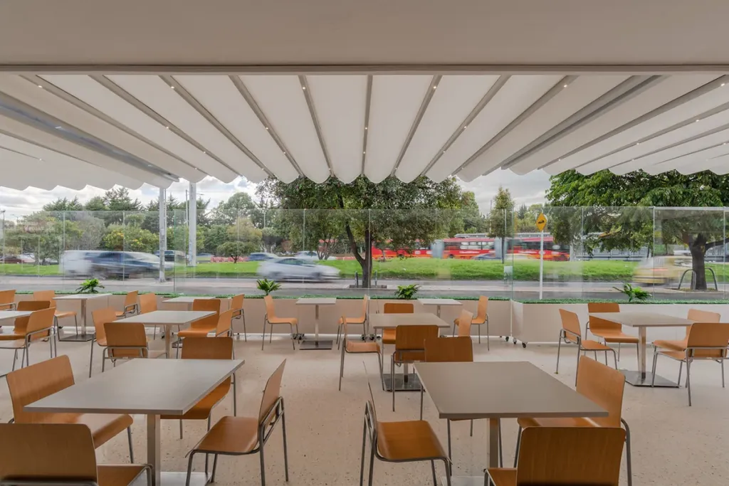 Patio de comidas cubierto con pérgola PergoTek Romano de gran formato junto a un parque