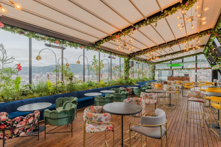 Pérgola retráctil PergoTek abierta sobre el rooftop bar del Hotel W en Bogotá, con cerramiento en vidrio y vista a los cerros