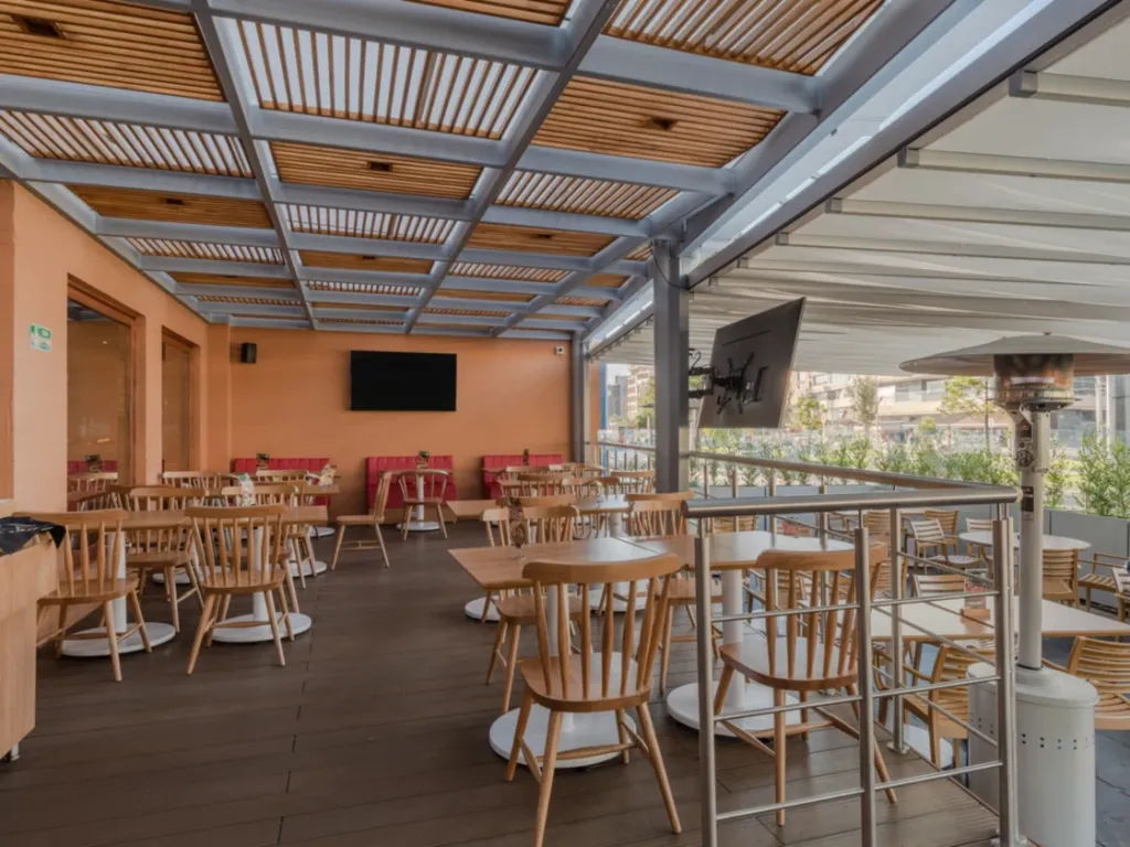 Terraza de café cubierta con pérgola retráctil PergoTek de lona tensa y lamas de madera
