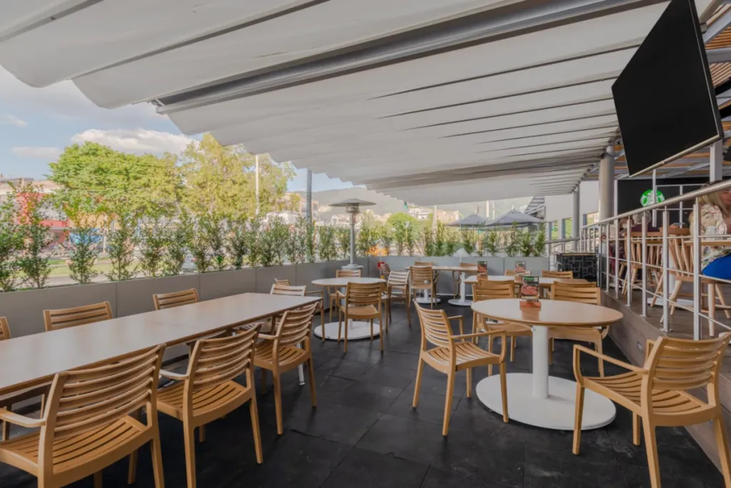 Comedor de restaurante al aire libre cubierto con pérgola retráctil PergoTek de lona tensa