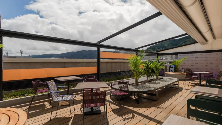 Pérgola retráctil PergoTek abierta sobre postes en la terraza de un restaurante, con la lona recogida y el cielo a la vista