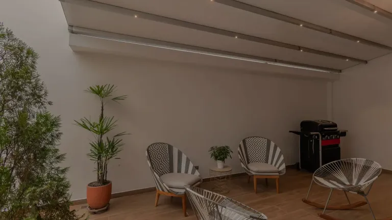 pérgola PergoTek con la lona extendida sobre la terraza de un apartamento, con luces led integradas