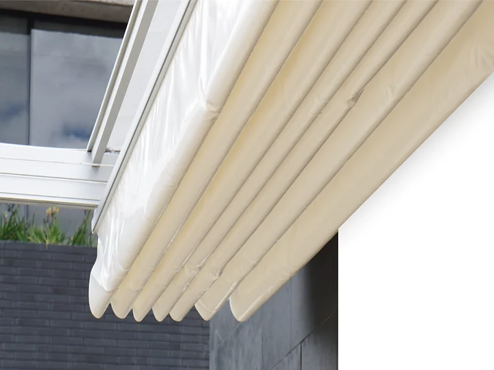 Palillería de aluminio con la lona PVC recogida en el alero de una pérgola retráctil PergoTek