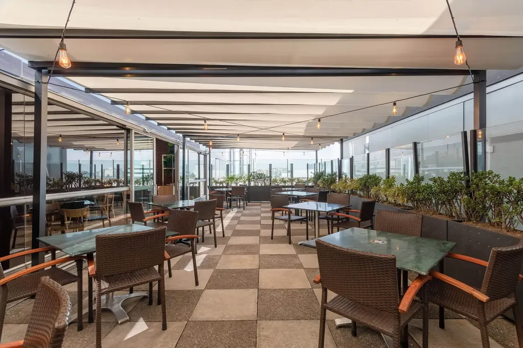 cubierta retráctil desplegada de extremo a extremo sobre las mesas de la terraza del restaurante