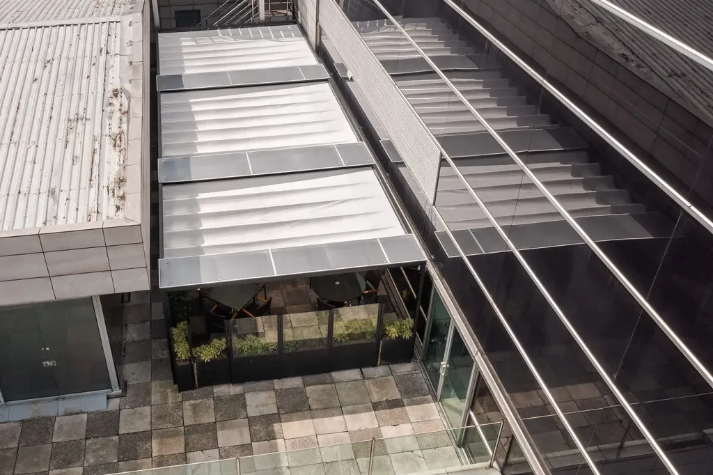 la lona de la cubierta retráctil plegada sobre su estructura de aluminio, vista desde arriba