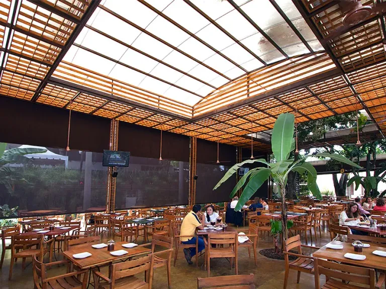 Cubierta en policarbonato con estructura en acero y paneles de madera teca sobre el patio de comidas de un restaurante