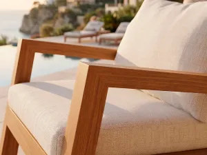 Detalle del ensamble en madera teca del brazo de la Poltrona Morros, con vista de piscina al fondo