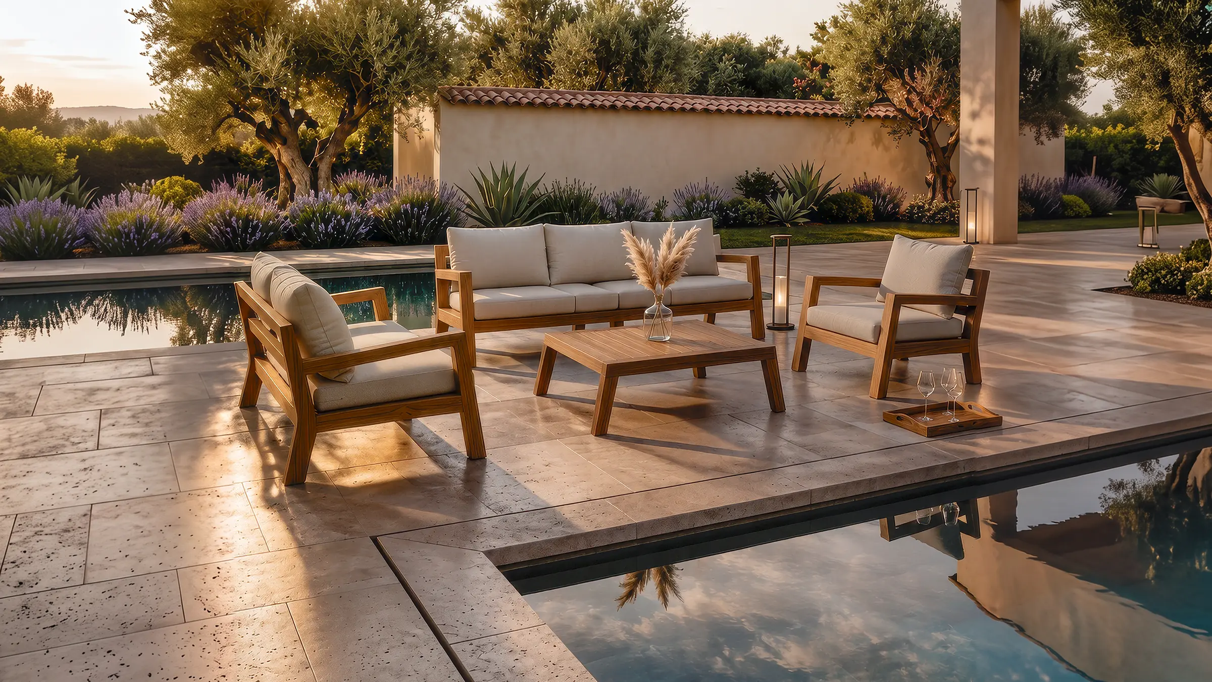 Conjunto de sofá y poltronas Morros en teca sobre una terraza con piscina al atardecer