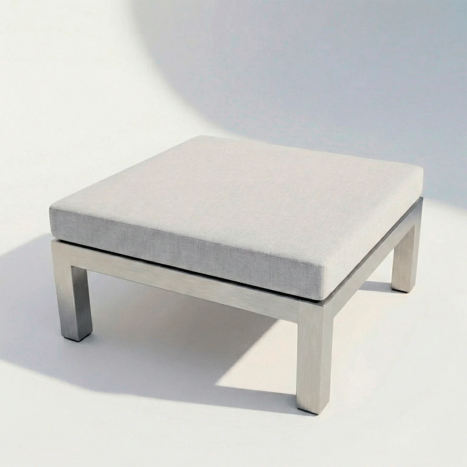 Pouf Montecarlo en aluminio con cojín, vista en perspectiva sobre fondo blanco de estudio