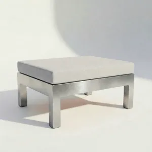 Pouf Montecarlo en aluminio con cojín, vista lateral sobre fondo de estudio