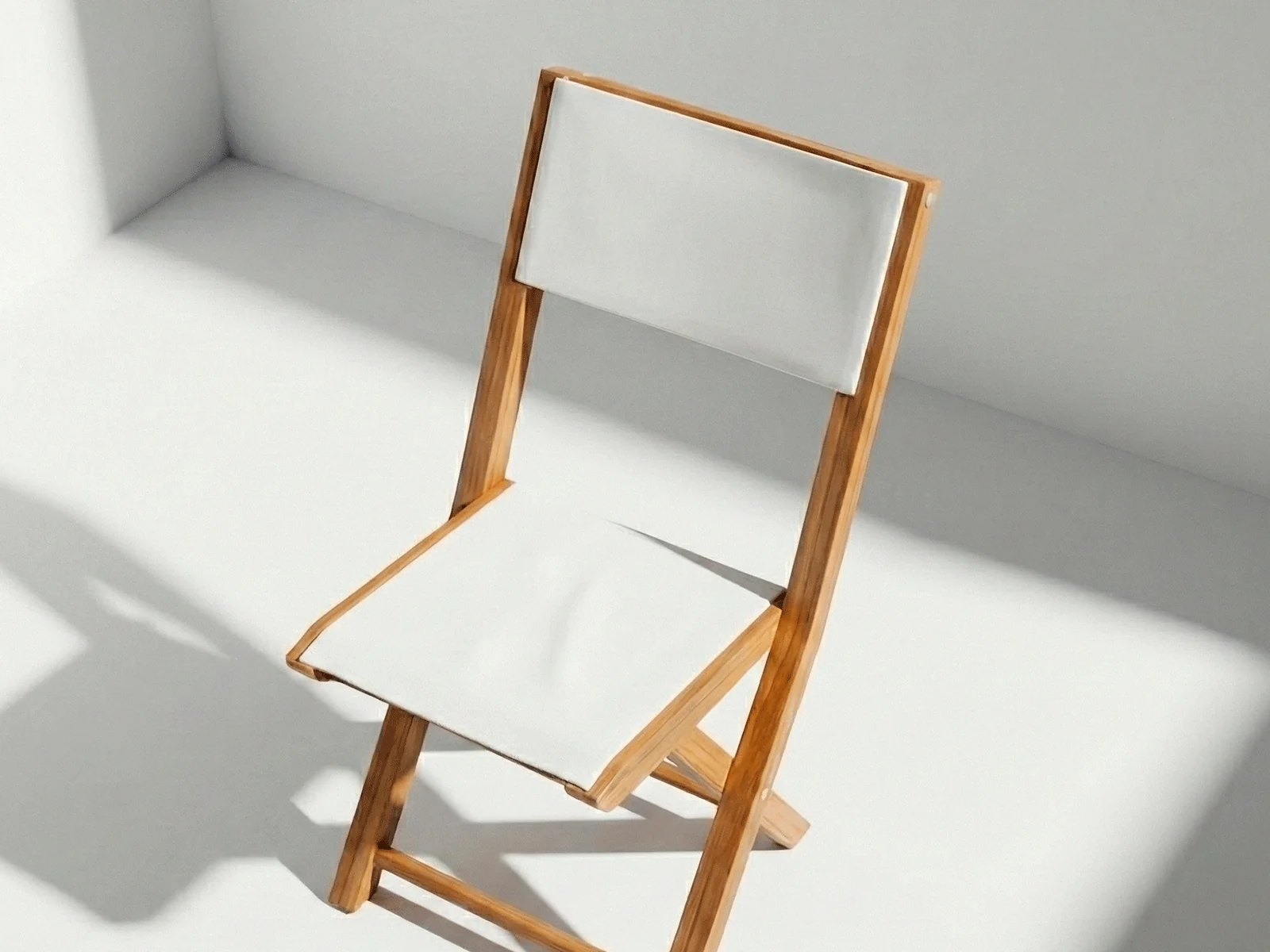 Silla plegable Kioto en madera teca y malla técnica, vista en perspectiva sobre fondo blanco de estudio