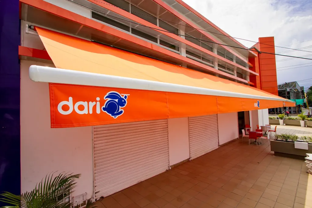 Sombralina en lona naranja con la marca del comercio impresa, instalada en la fachada de un local