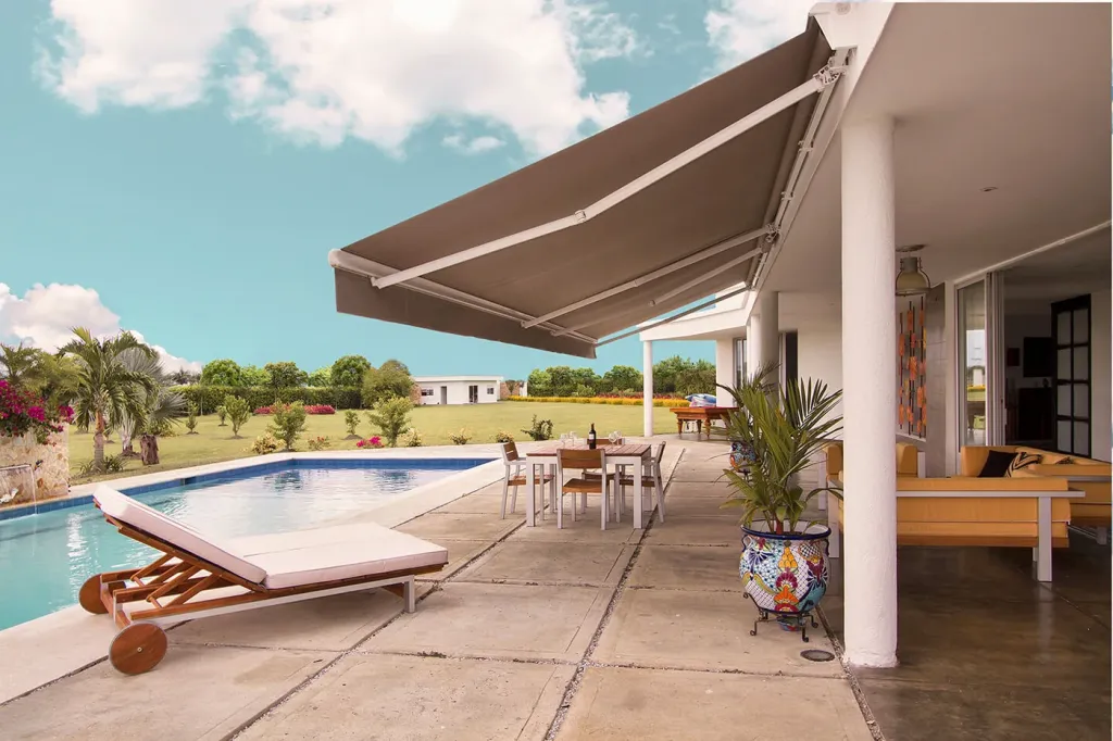 Sombralina desplegada sobre el corredor de una casa campestre junto a la piscina