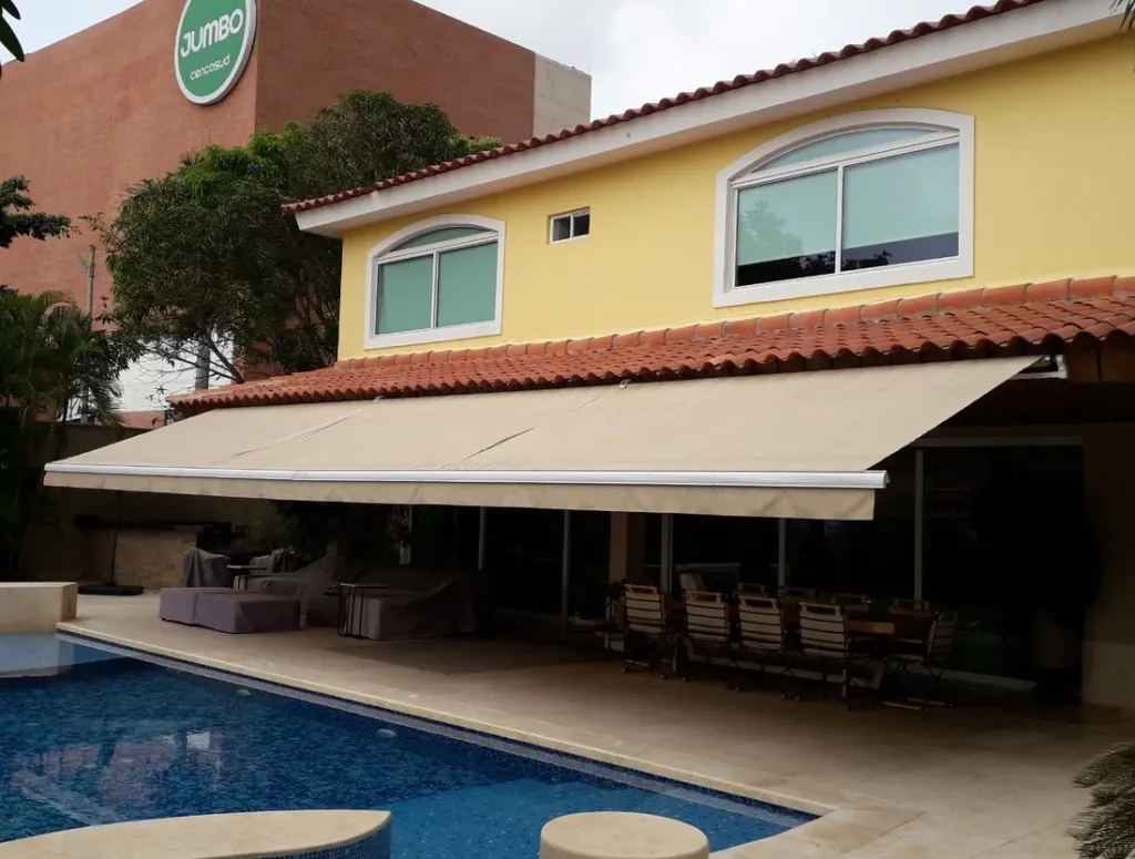 Sombralina de gran longitud instalada en la fachada de una vivienda, sobre la terraza junto a la piscina