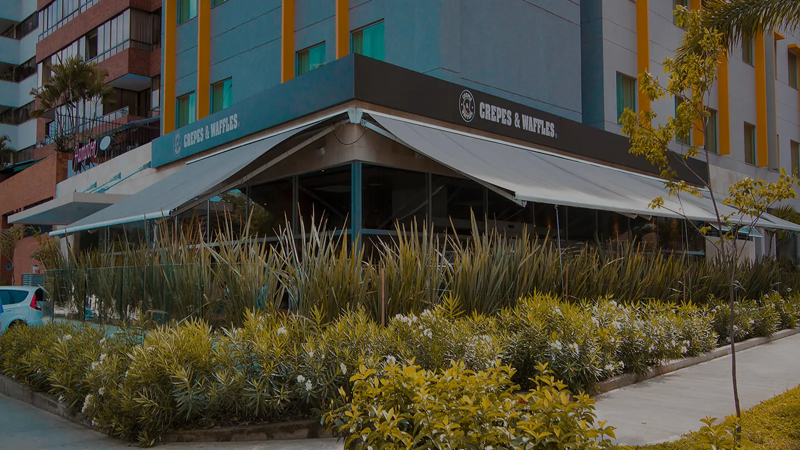 Supersombralina de gran formato cubriendo la terraza en esquina de un restaurante, con la parte fija y la enrollable desplegadas