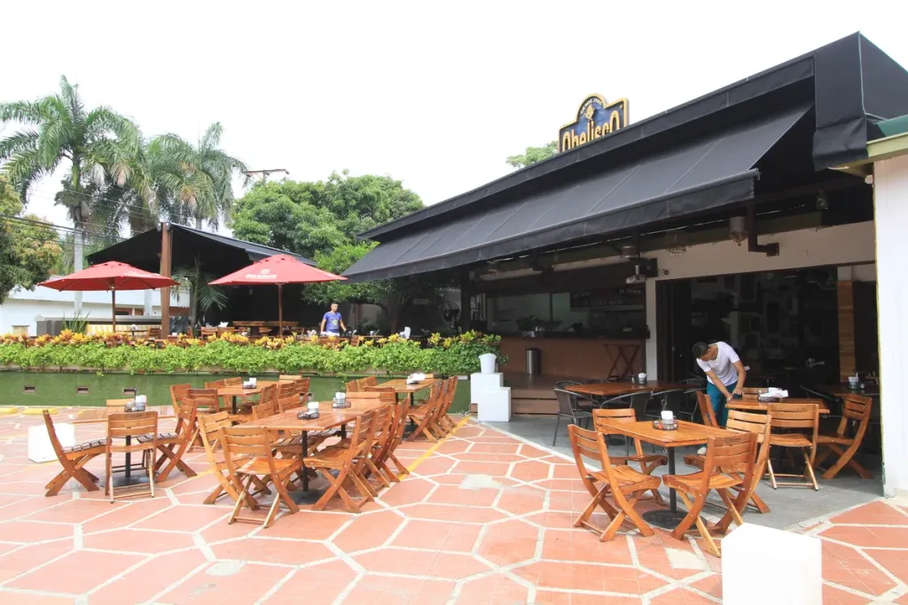Supersombralina en lona oscura sobre la terraza de mesas de madera de un restaurante