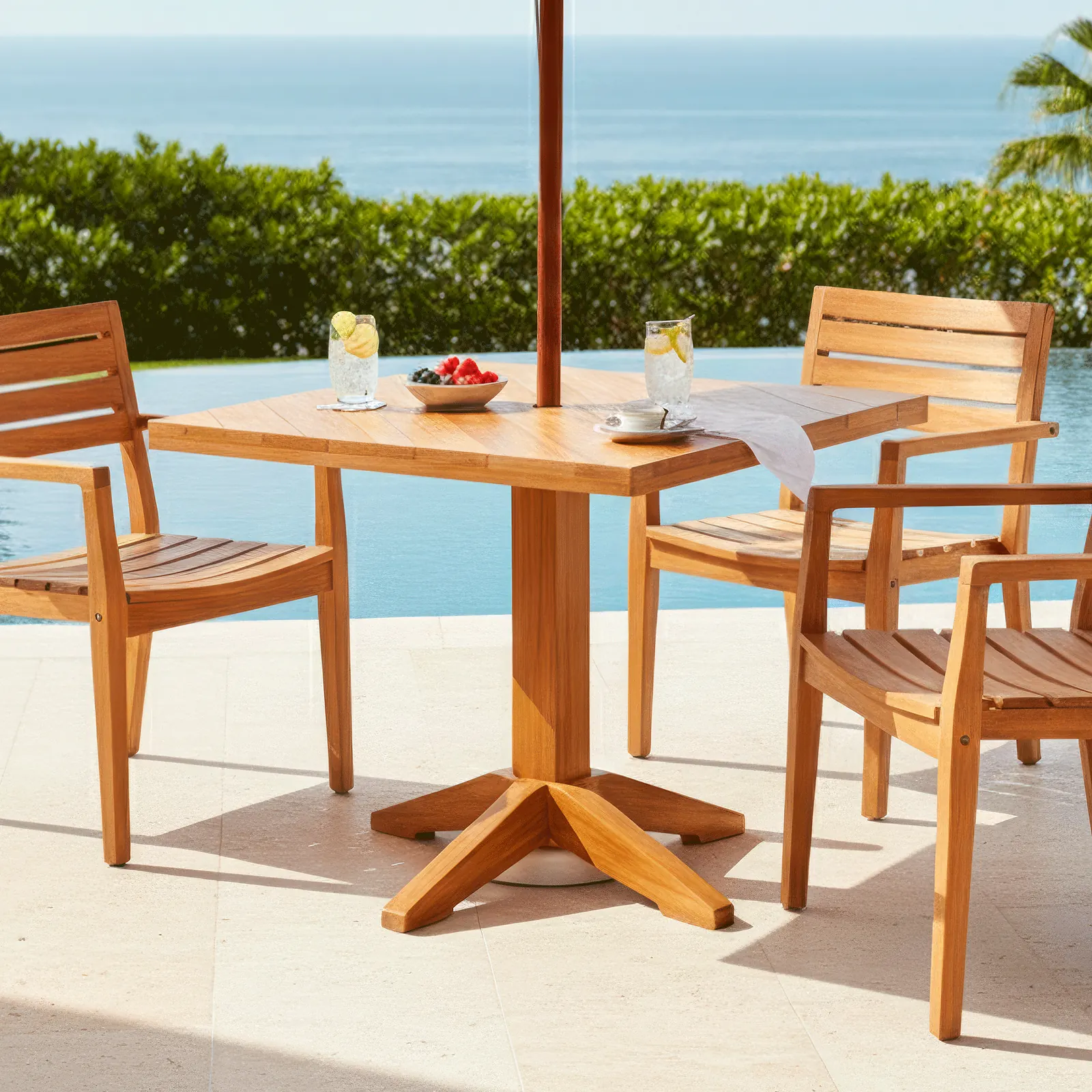 Mesa Putumayo cuadrada en madera teca de la Colección Amazonas, en una terraza junto a la piscina