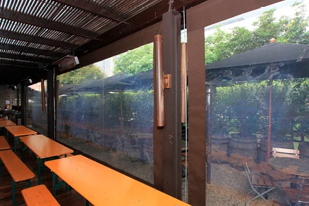 Toldos verticales Baneta Vertical en clear transparente cerrando una terraza con mesas y bancas de madera