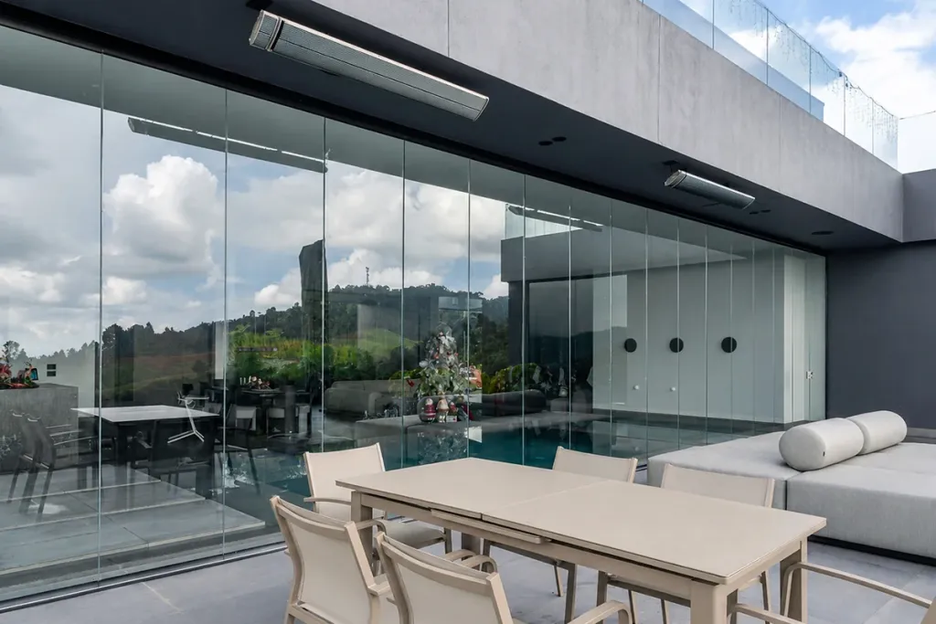 Comedor exterior cerrado con FlexiGlass junto a la piscina de una casa