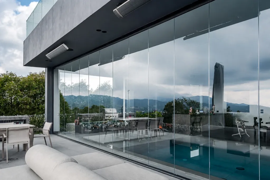 Sala exterior con los paneles FlexiGlass abiertos hacia la piscina