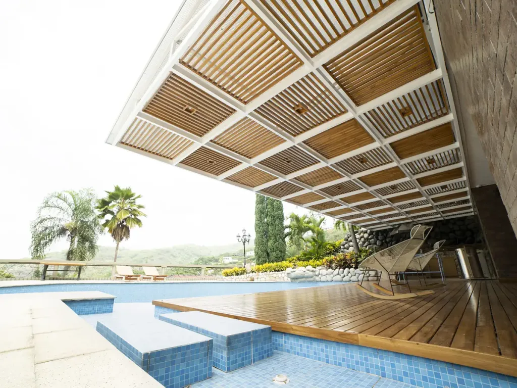 Pérgola fija de aluminio sobre la zona social exterior de una vivienda, con comedor y sofás bajo la cubierta