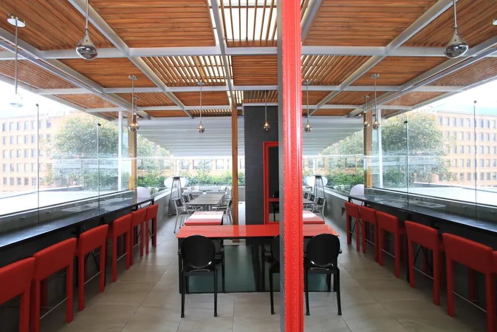 Terraza de restaurante cubierta con pérgola fija de aluminio y mesas dispuestas debajo