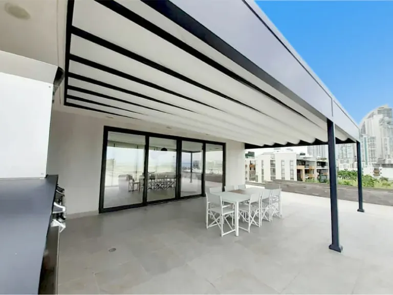 PergoTek Deco Ondulado con la lona recogida en ondas sobre la terraza de un apartamento urbano