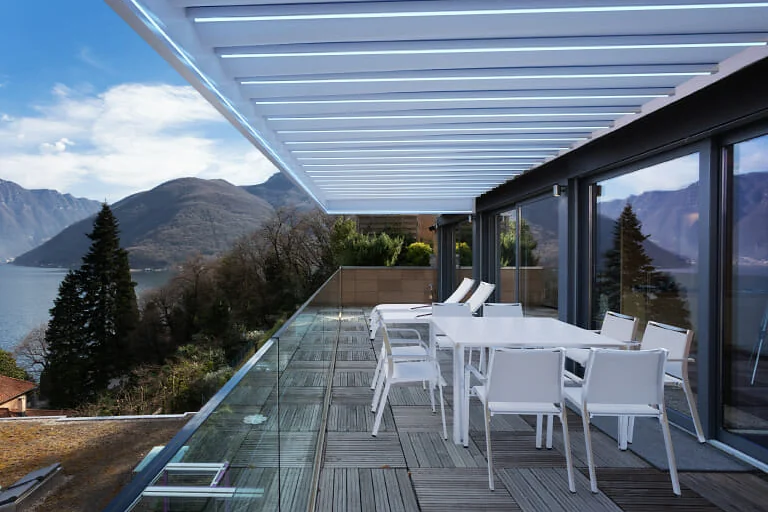 PergoTek Deco Ondulado sobre una terraza de comedor exterior con vista a un lago y montañas