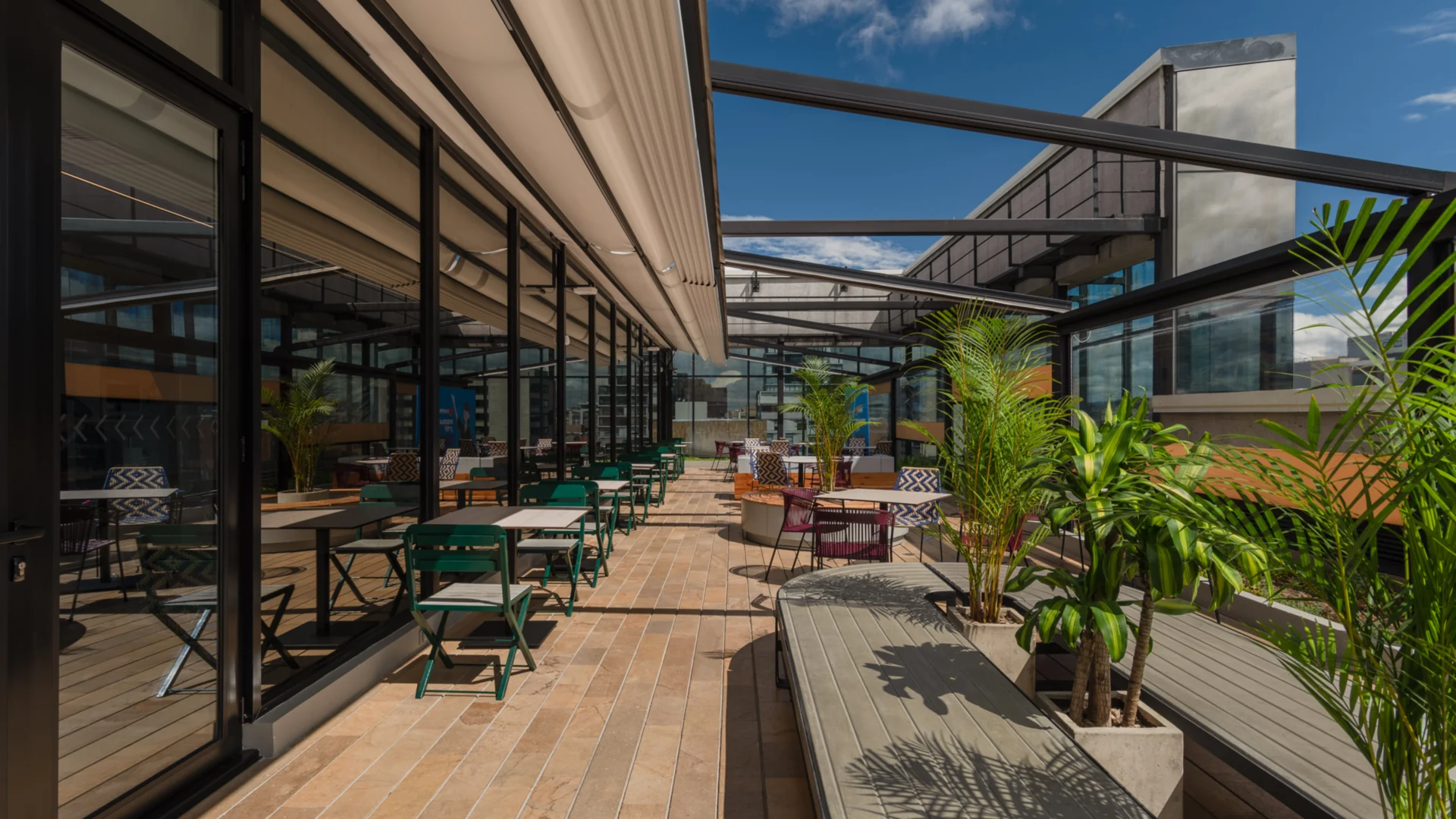 Pérgola retráctil PergoTek La Roche, abierta sobre la terraza con la estructura y el cielo a la vista