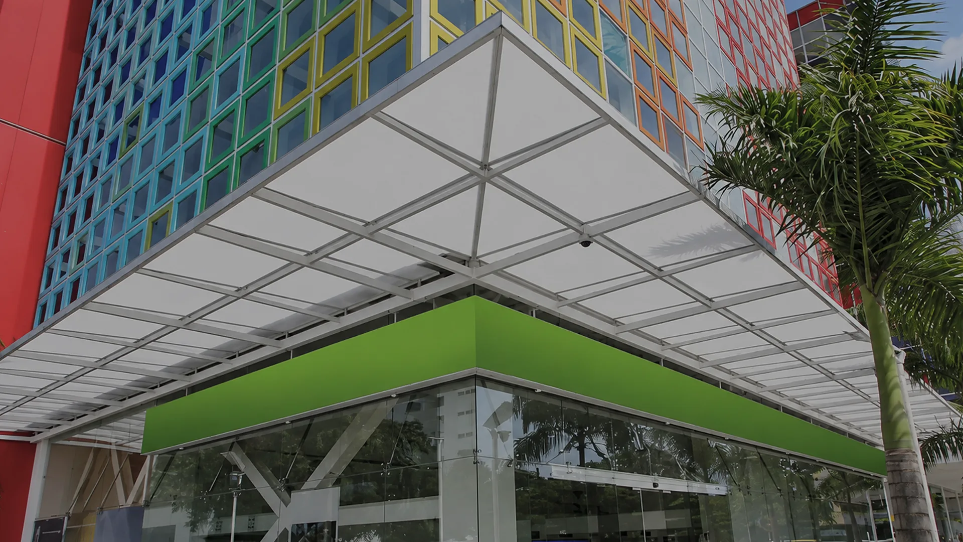 Cubierta fija de policarbonato sobre el acceso de un edificio de fachada de colores