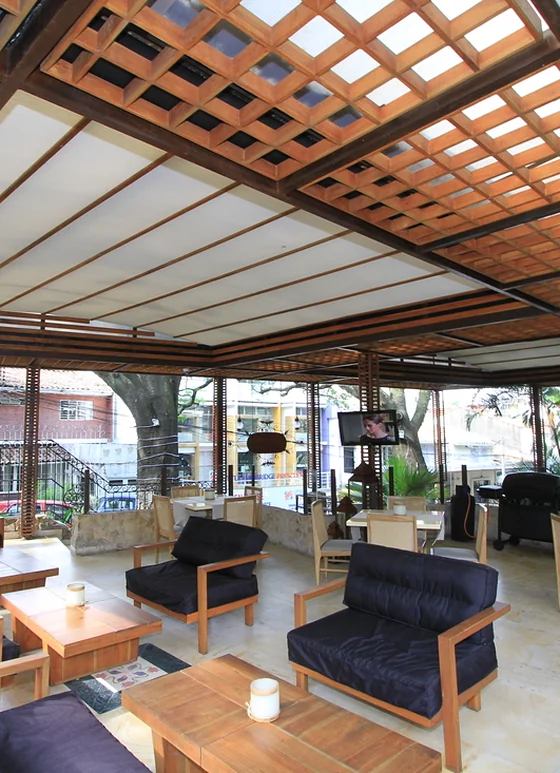 Patio de comidas cubierto con pérgola fija de estructura en acero y paneles de madera teca