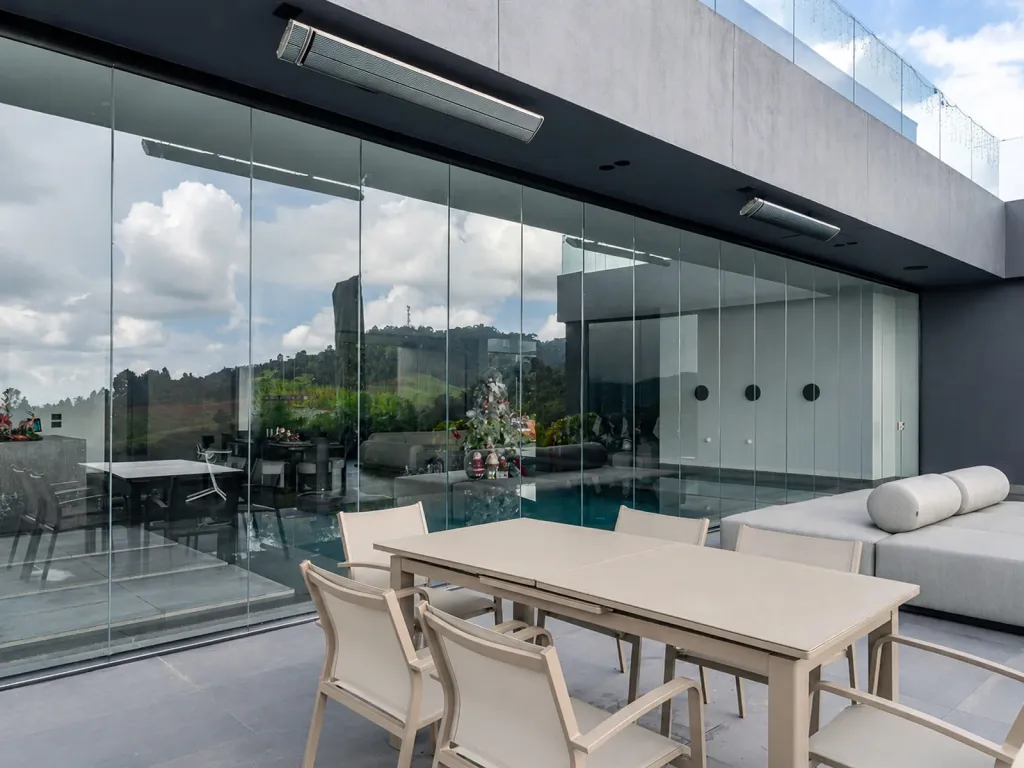 Cerramiento FlexiGlass en la terraza de una casa con piscina, comedor exterior y calentadores