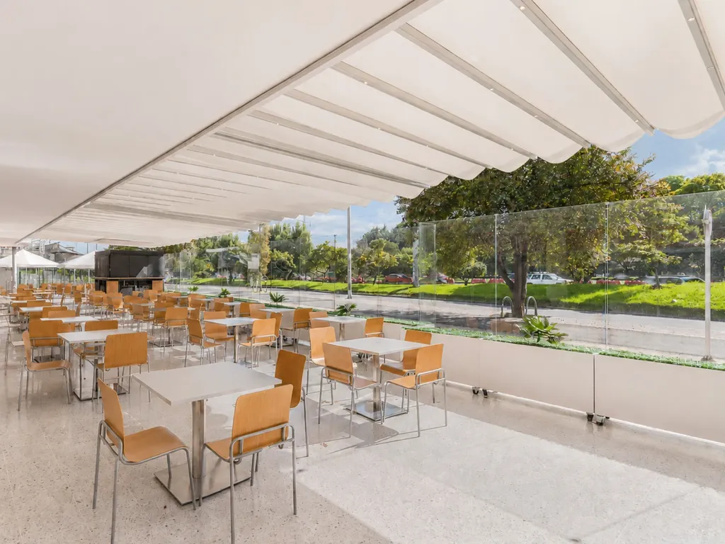 Paneles FlexiWind bajos en el perímetro de una terraza de restaurante bajo un toldo blanco
