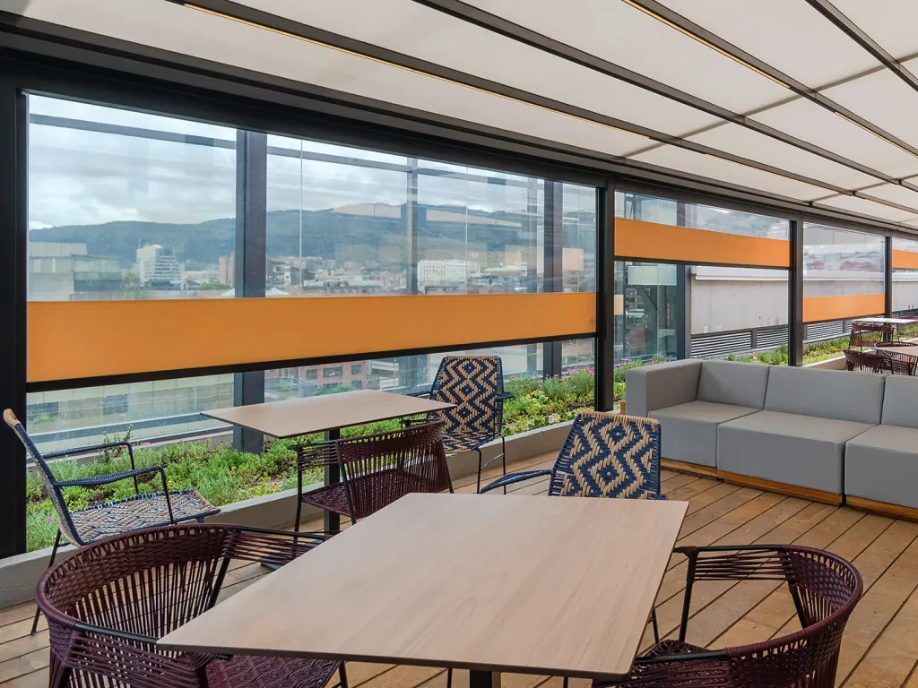 Cerramiento FlexiZipp junto al comedor de una terraza, con la franja naranja de la fachada a la vista