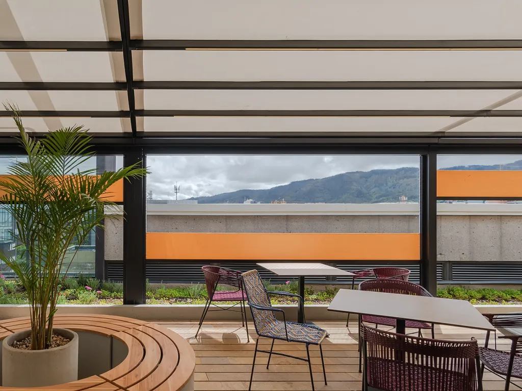 Terraza con mesas bajo la pérgola y cortinas FlexiZipp recogidas, con montañas al fondo