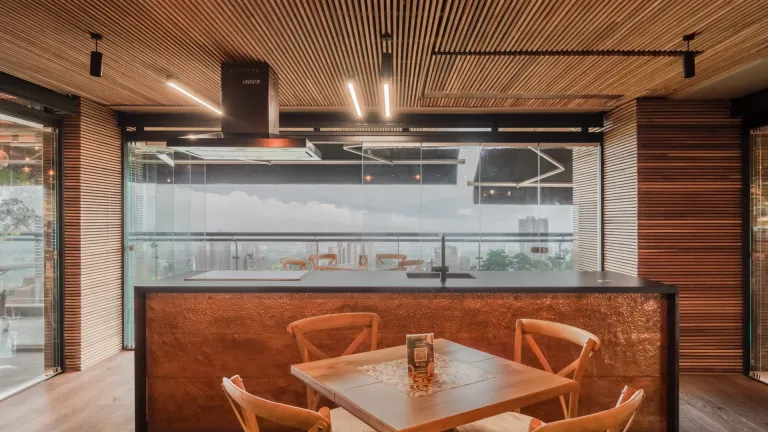 Cerramiento de vidrio templado tras la barra del restaurante de Mercaorgánico, con mesa de madera en primer plano