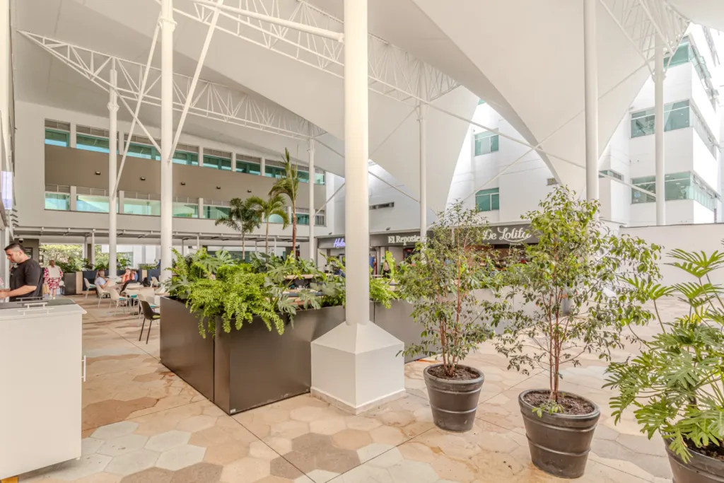 Mástiles blancos y jardineras bajo la cubierta de membrana de la Clínica Las Américas
