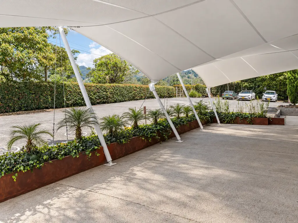 Zona exterior sombreada por membranas tipo pañuelo y jardineras en el Gym Naty Marín