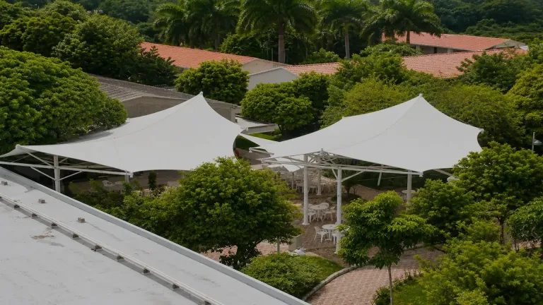Membrana autoportante en ángulo sobre una plazoleta con mesas al aire libre