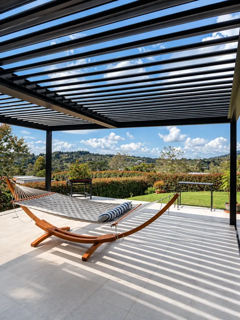 Pérgola bioclimática PergoLam sobre una terraza con hamaca y jardín