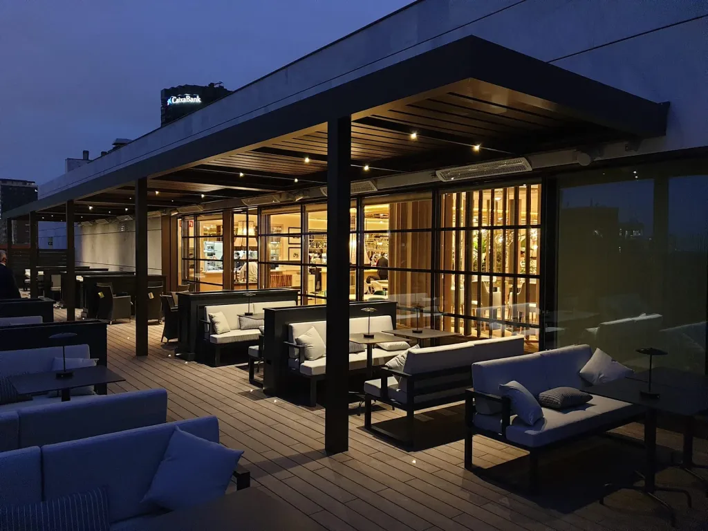 Pérgola bioclimática PergoLam iluminada sobre la terraza de un restaurante al anochecer