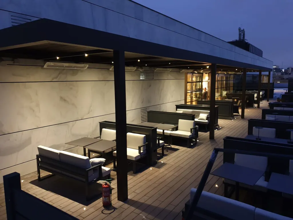 Pérgola bioclimática PergoLam sobre las salas lounge de la terraza de un restaurante
