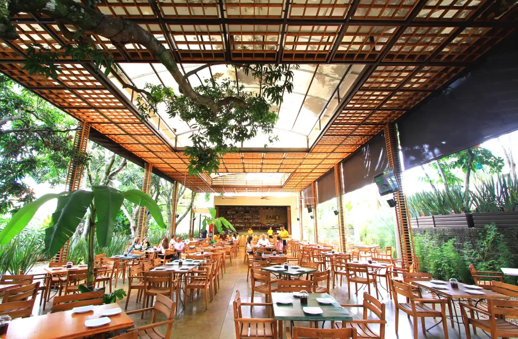 Pérgola fija en acero sobre el comedor del restaurante Faro en Cali, entre la vegetación