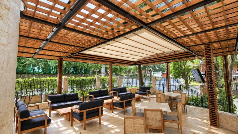 Pérgola fija en acero con paneles de madera teca sobre una sala exterior