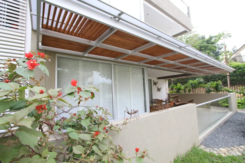 Pérgola fija en aluminio sobre la terraza de una vivienda con bugambilias