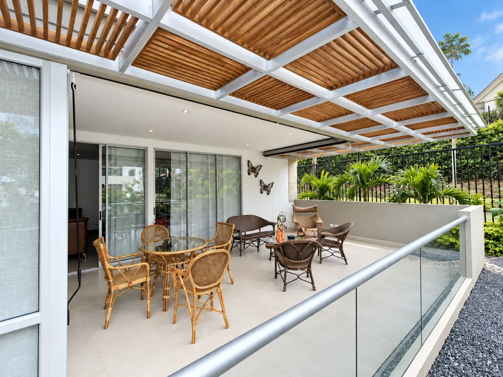 Pérgola fija en aluminio sobre la terraza de un apartamento con sillas de mimbre