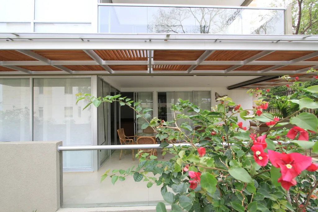 Pérgola fija en aluminio sobre la terraza de una vivienda, vista entre flores