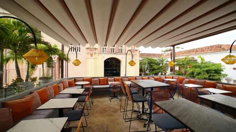 Pérgola retráctil de tela ondulada sobre el rooftop del restaurante Buena Vida, con sofás corridos y mesas