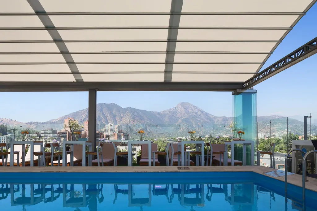 Pérgola retráctil PergoDom junto a la piscina del rooftop del hotel Noi, con las montañas al fondo